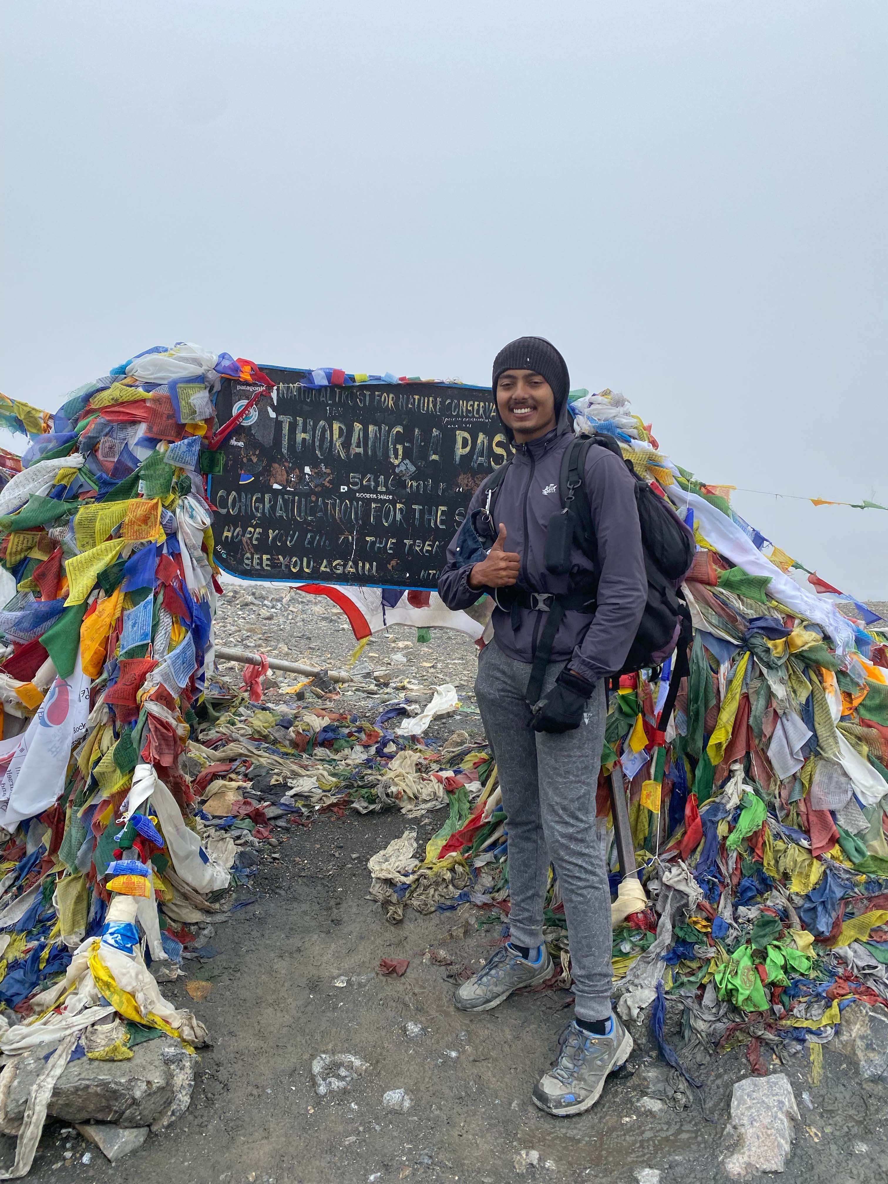 Trekker of Trek 8586 posing infront of signage board in Thorangla Pass adventure on the Tilicho Trek, part of the Annapurna Trek, on Trek 8586