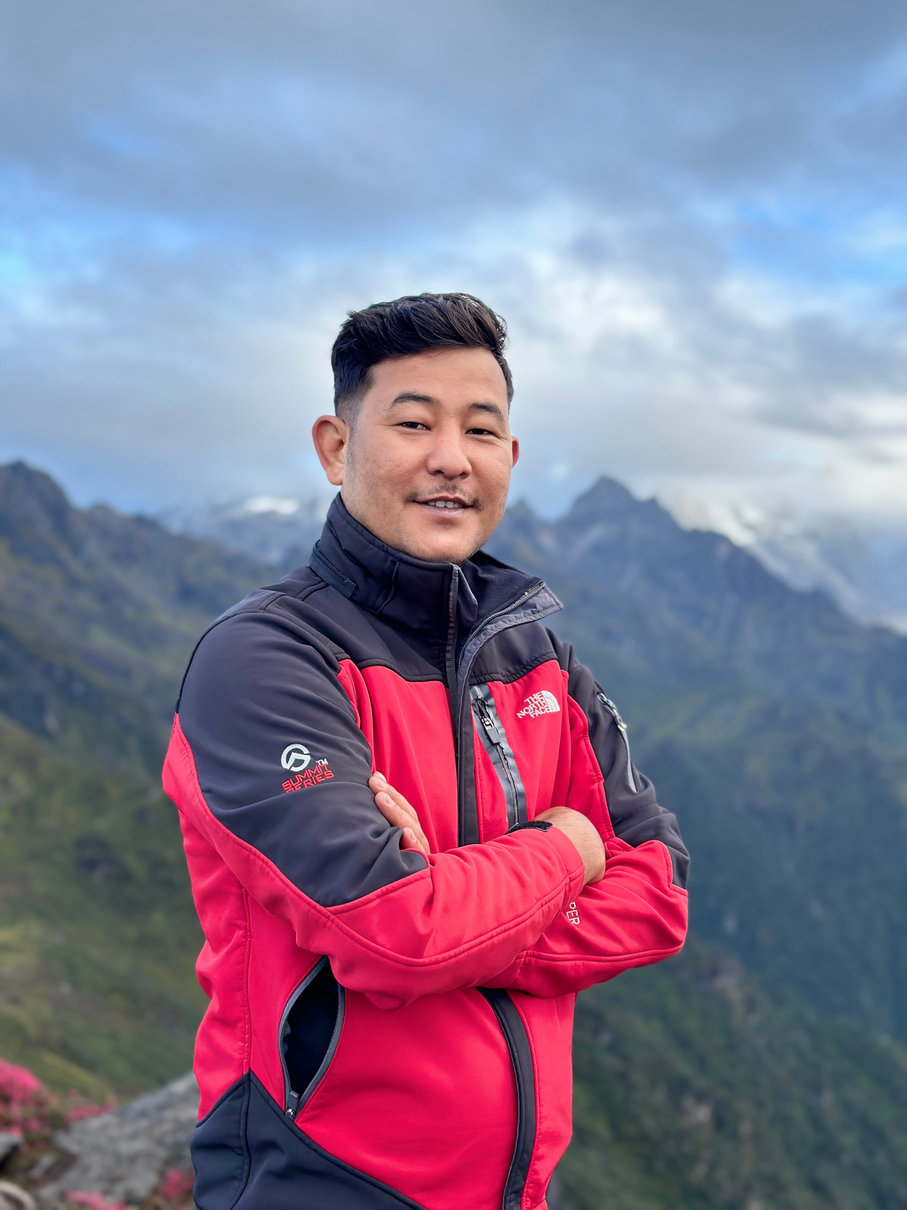 Sujan Acharya posing in front of a majestic mountain, showcasing the breathtaking landscapes of Nepal, ideal for adventurous trekking journeys.